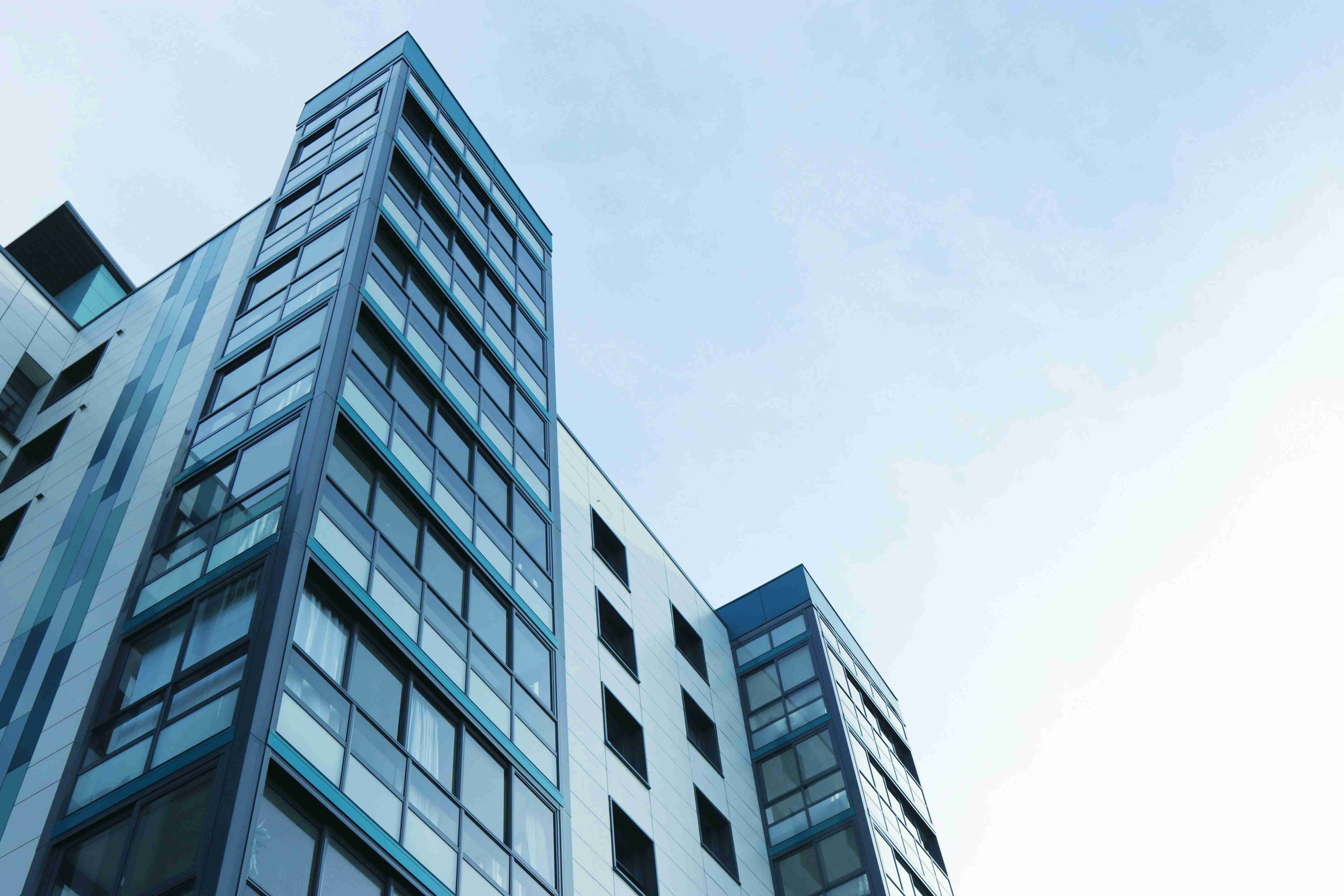 A modern residential tower viewed from street level — Real Estate
