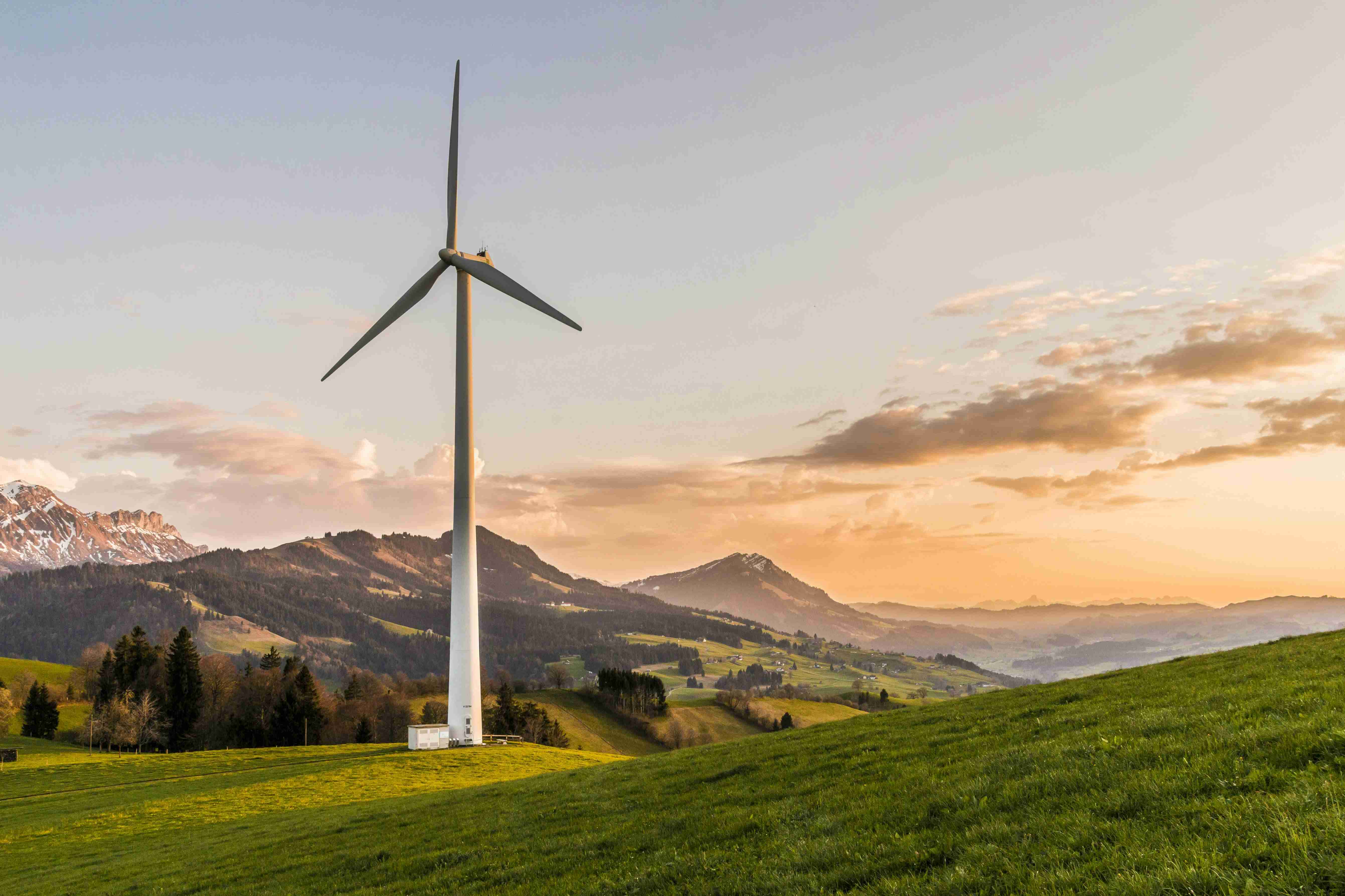 A wind turbine standing against a sunset sky — Sustainability & Technology