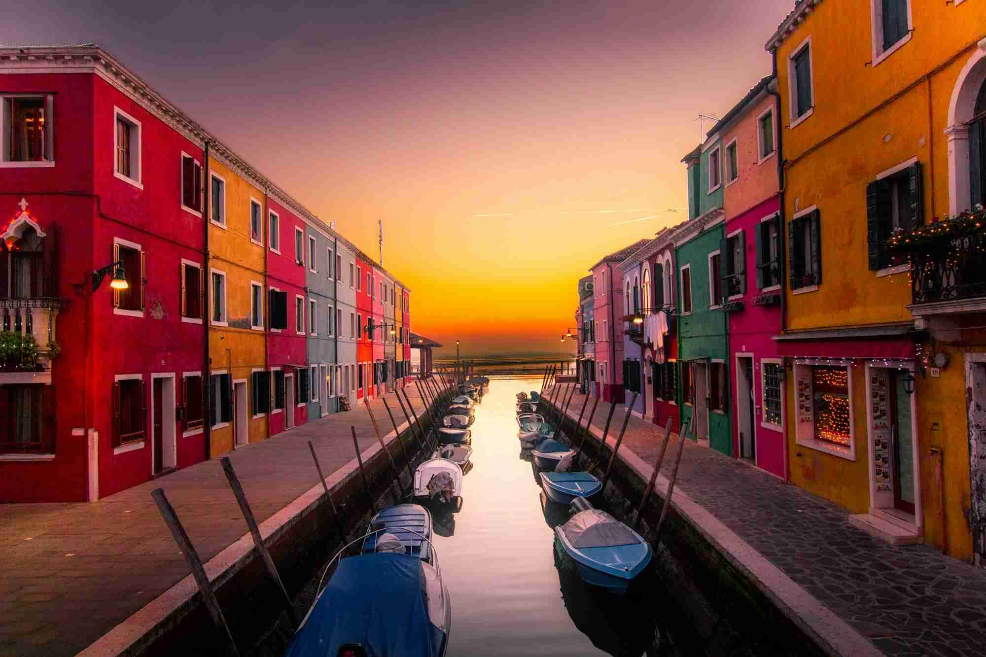 A canal between brightly coloured houses at sunset — Tourism