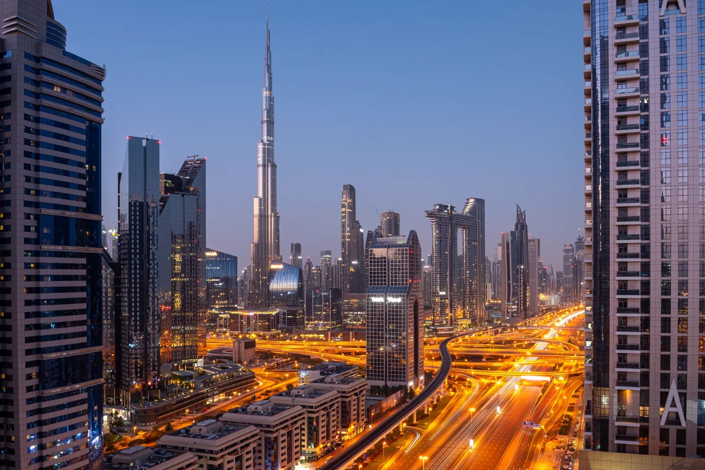 Dubai skyline and illuminated roads at blue hour.